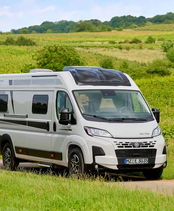 Familie im Campingbus: Vater und Kinder spielen am Tisch, Mutter lächelt in der Küche.